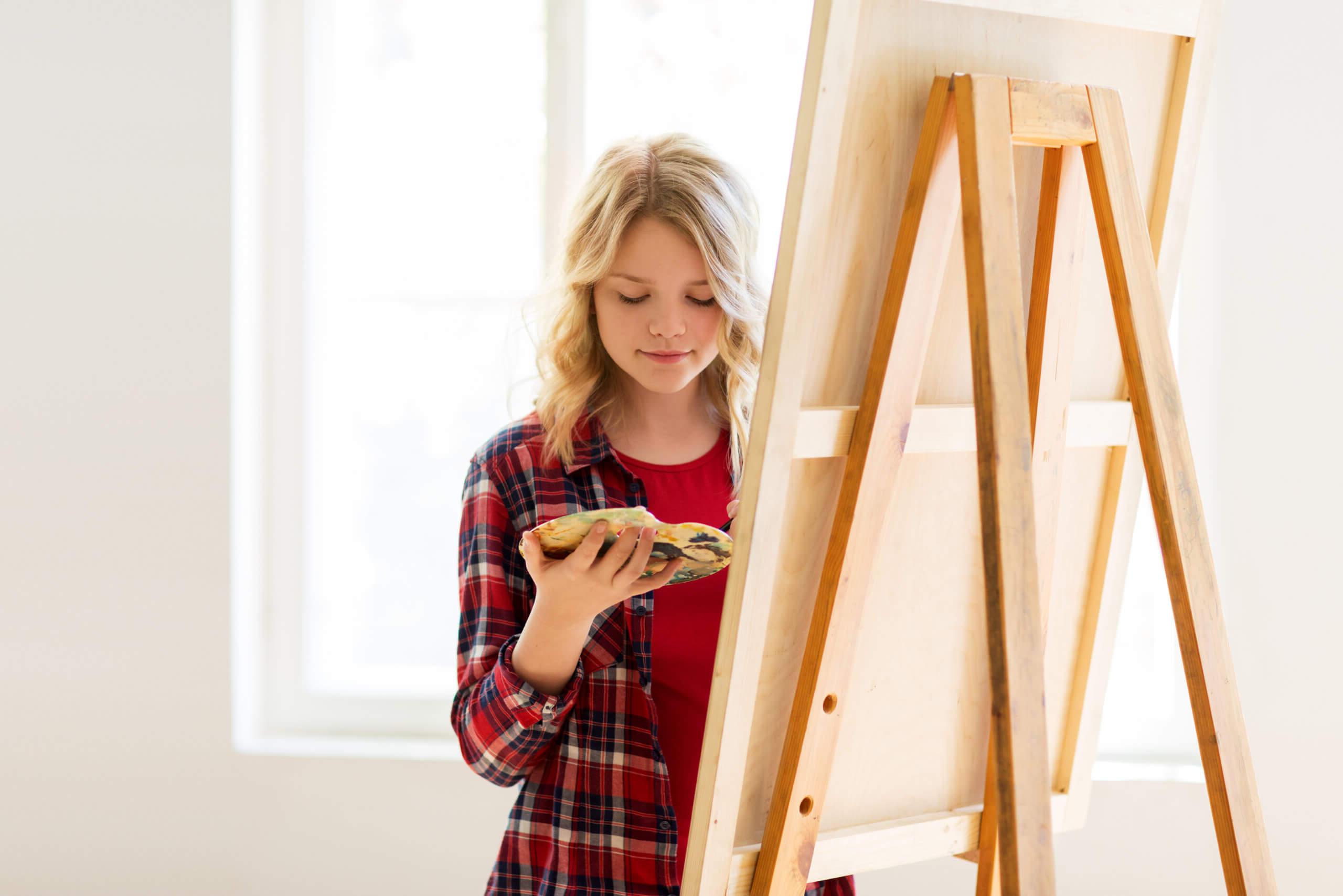 student girl with easel painting at art school PVPQ9UA scaled